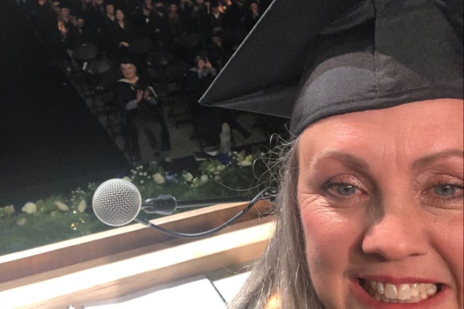 Christy Pittman smiles for selfie on stage at Commencement