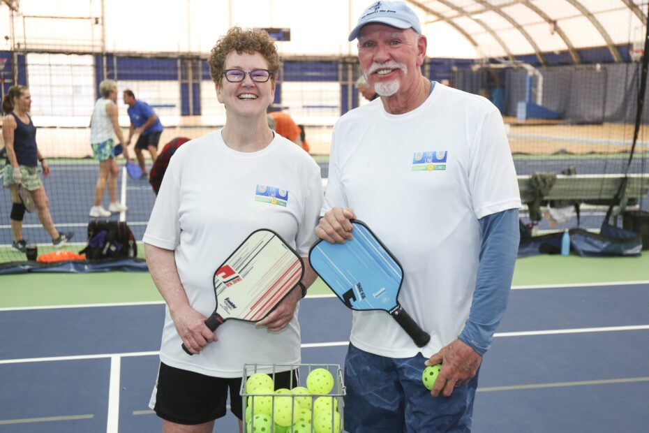 Two people with pickleball raquets and balls