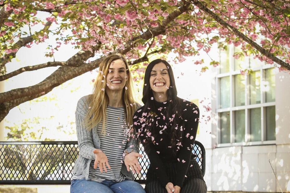 Seda Ellis, left, and her sister Klea Lamallari, right, sit on the Hardin Valley Campus under a dogwood tree