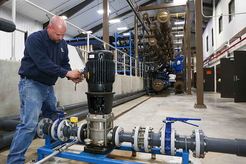 male working on a pump at a pipe system