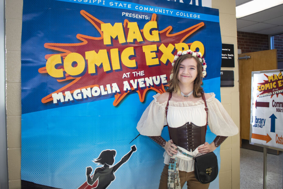 Student dressed up in front of Mag Comic Expo display in 2022