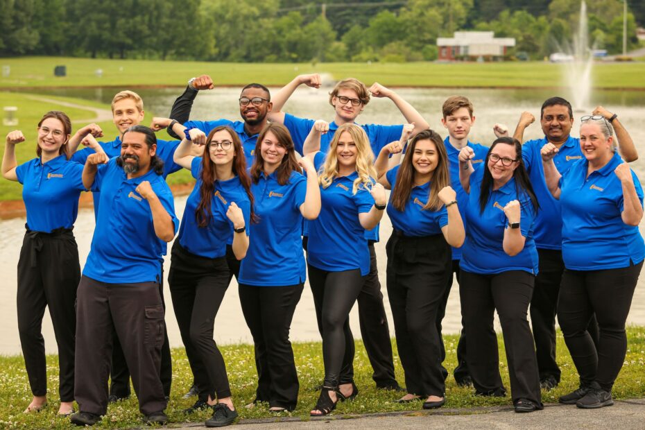 Pellissippi State New Student Orientation leaders pose by the pond with Pellissippi Strong arms.