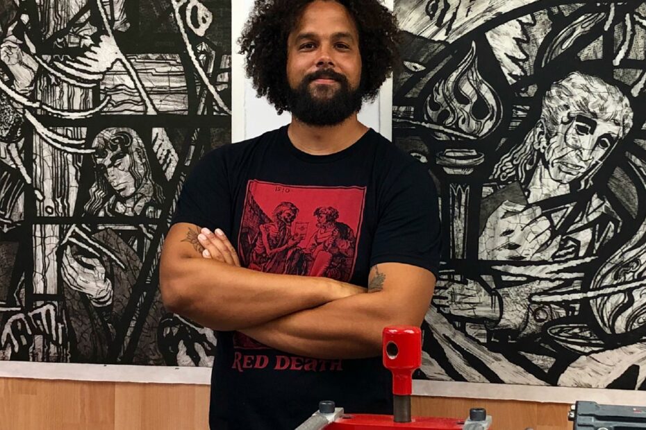 Artist Aaron Coleman in front of some of his prints