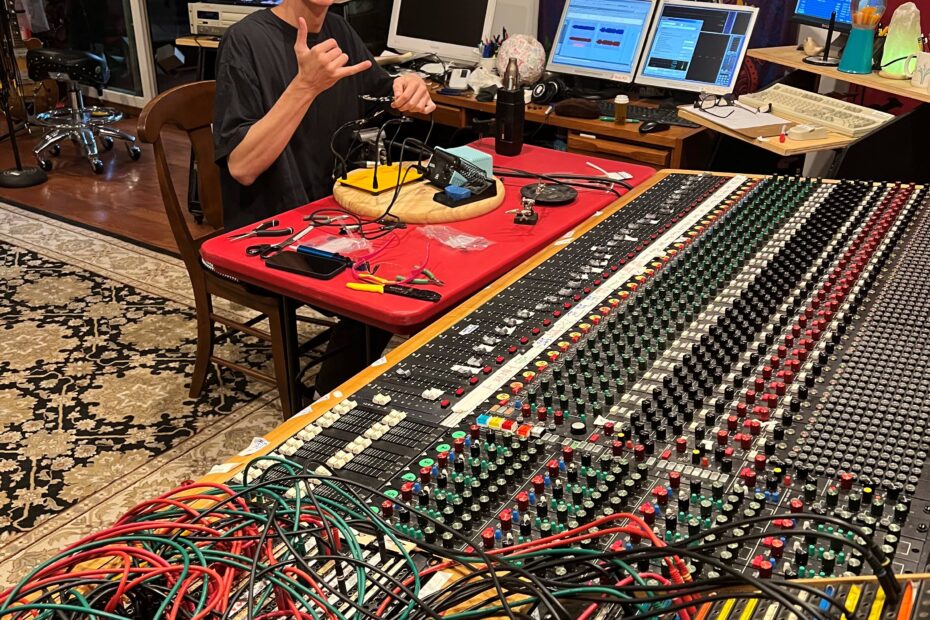 Benjamin Conner at an audio console with computers, mics, wires, etc.