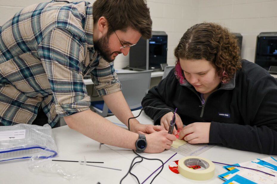 Pellissippi State Instructor Shane Terry, left, helps Ava Fain, a seventh grader at Coulter Grove Intermediate School in Maryville, learn how to use a 3D pen during a spring break camp on the college's Blount County Campus.